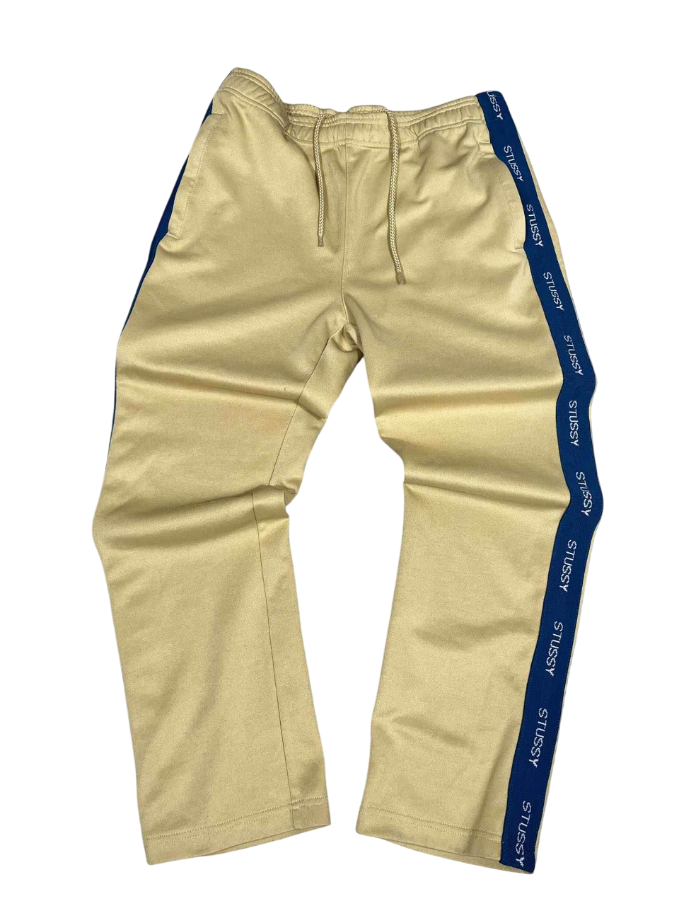 Bézs Stussy streetwear melegítőnadrág kék oldalsó csíkkal, vintage stílusban.