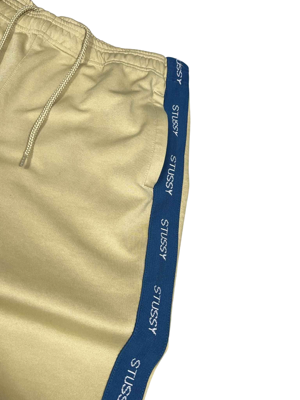 Bézs Stussy streetwear melegítőnadrág kék oldalsó csíkkal, vintage stílusban