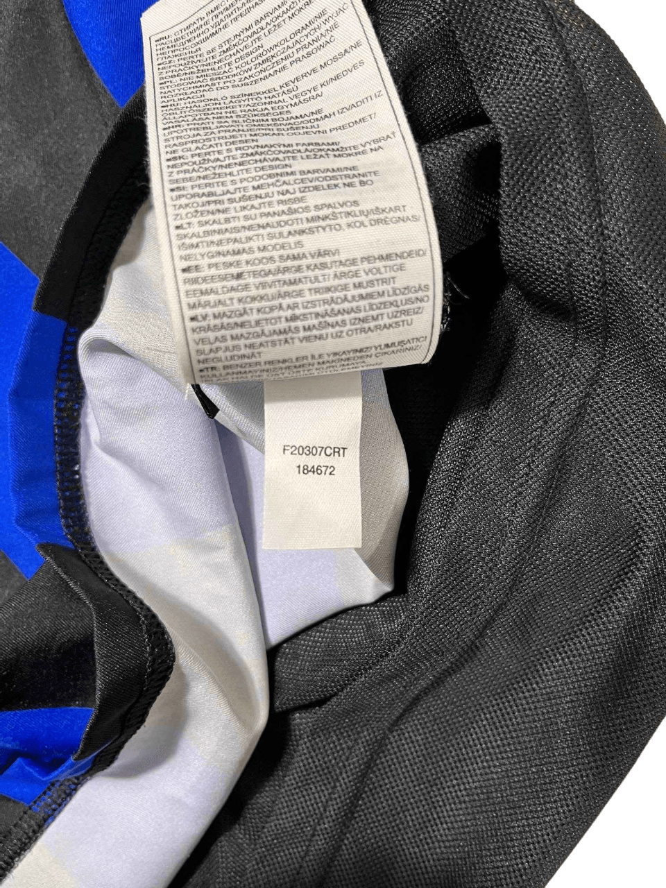 Ruhacímke fekete, kék és fehér vintage streetwear pulóver belsejében, anyagösszetétellel.