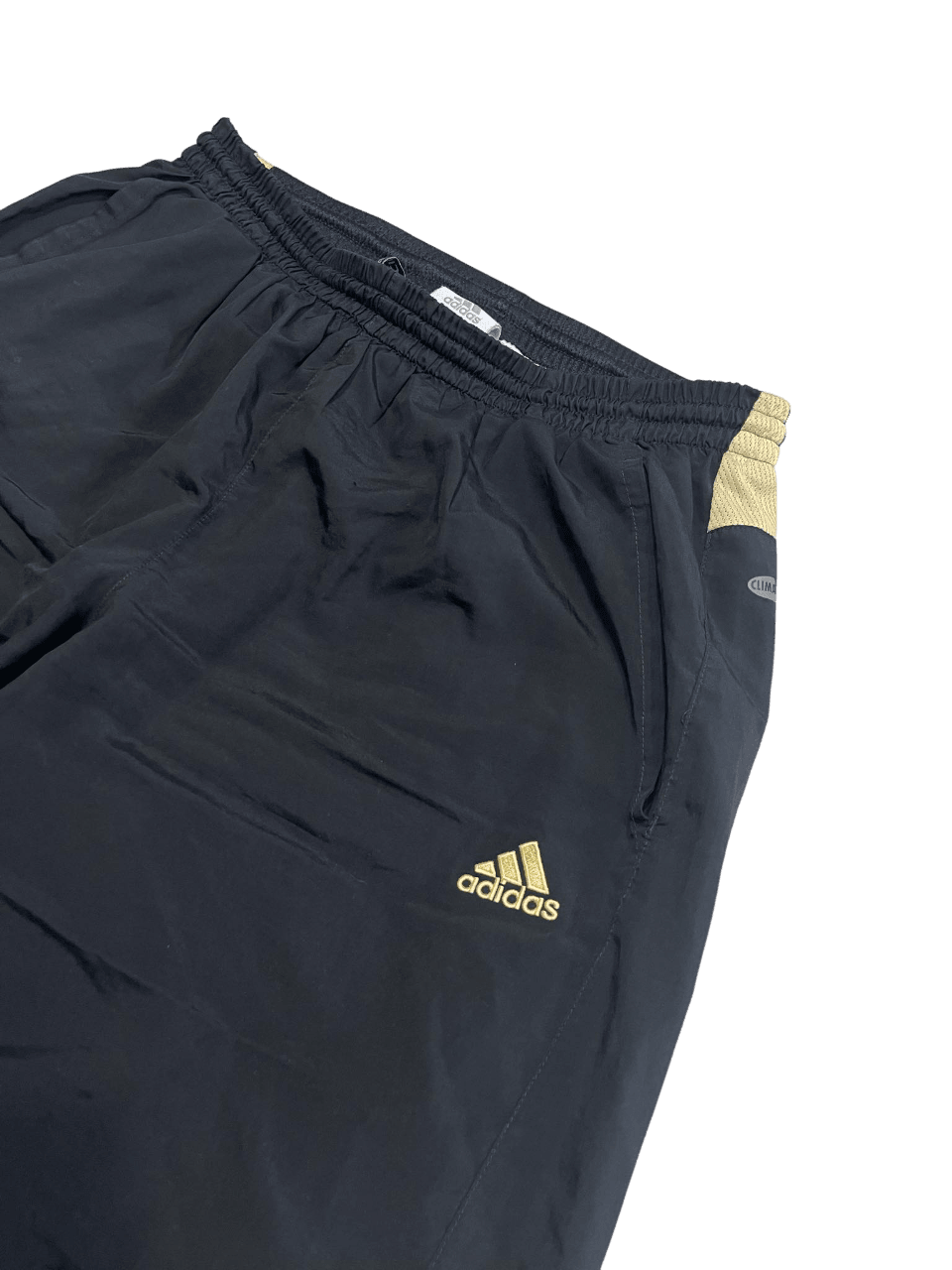 Fekete Adidas vintage melegítőnadrág arany logóval, streetwear stílusban.