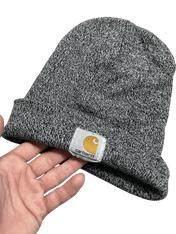 Szürke Carhartt kötött sapka kézben, streetwear stílus, márkajelzéssel az elején.